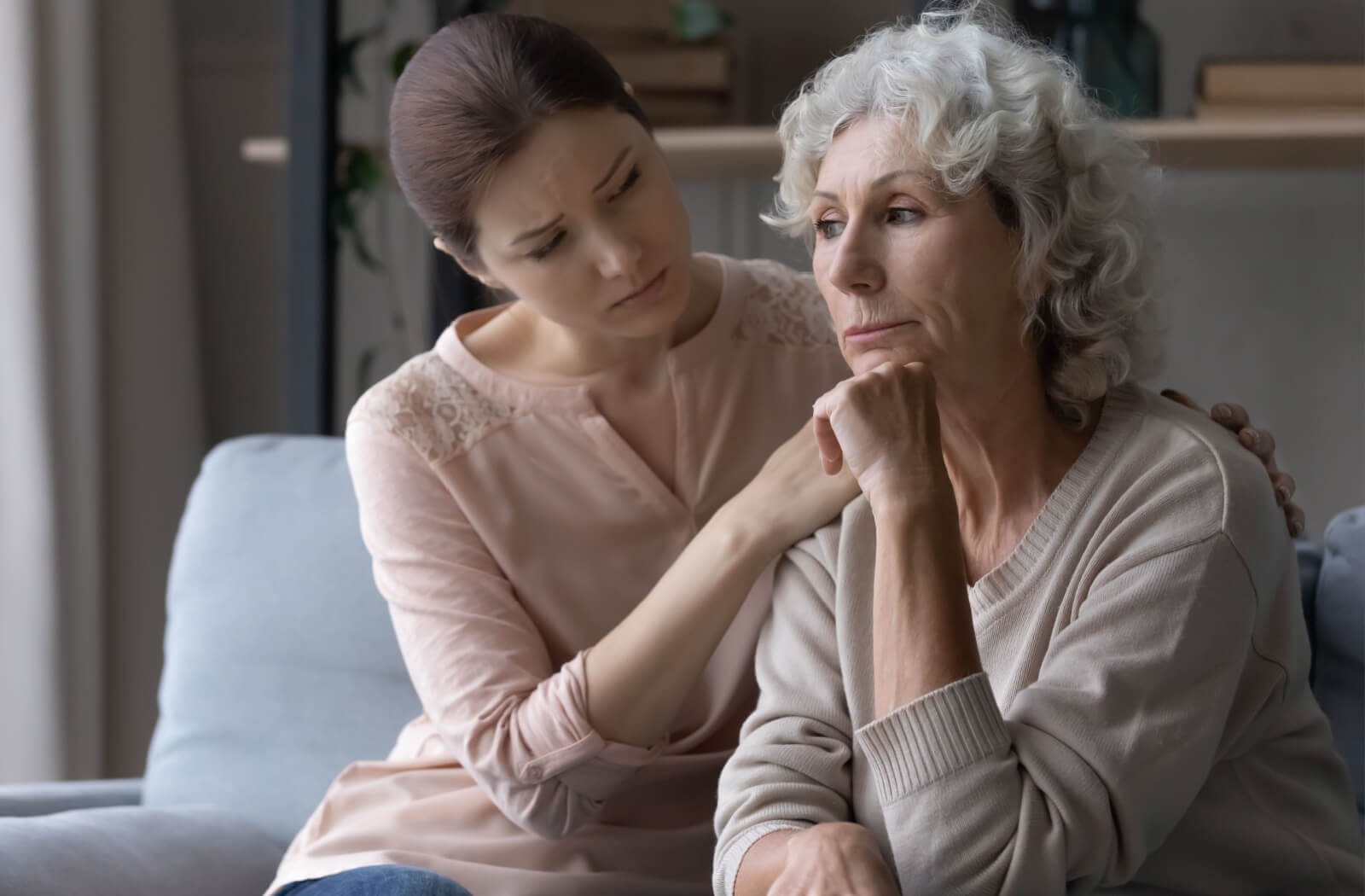 An adult child comforts their senior parent.