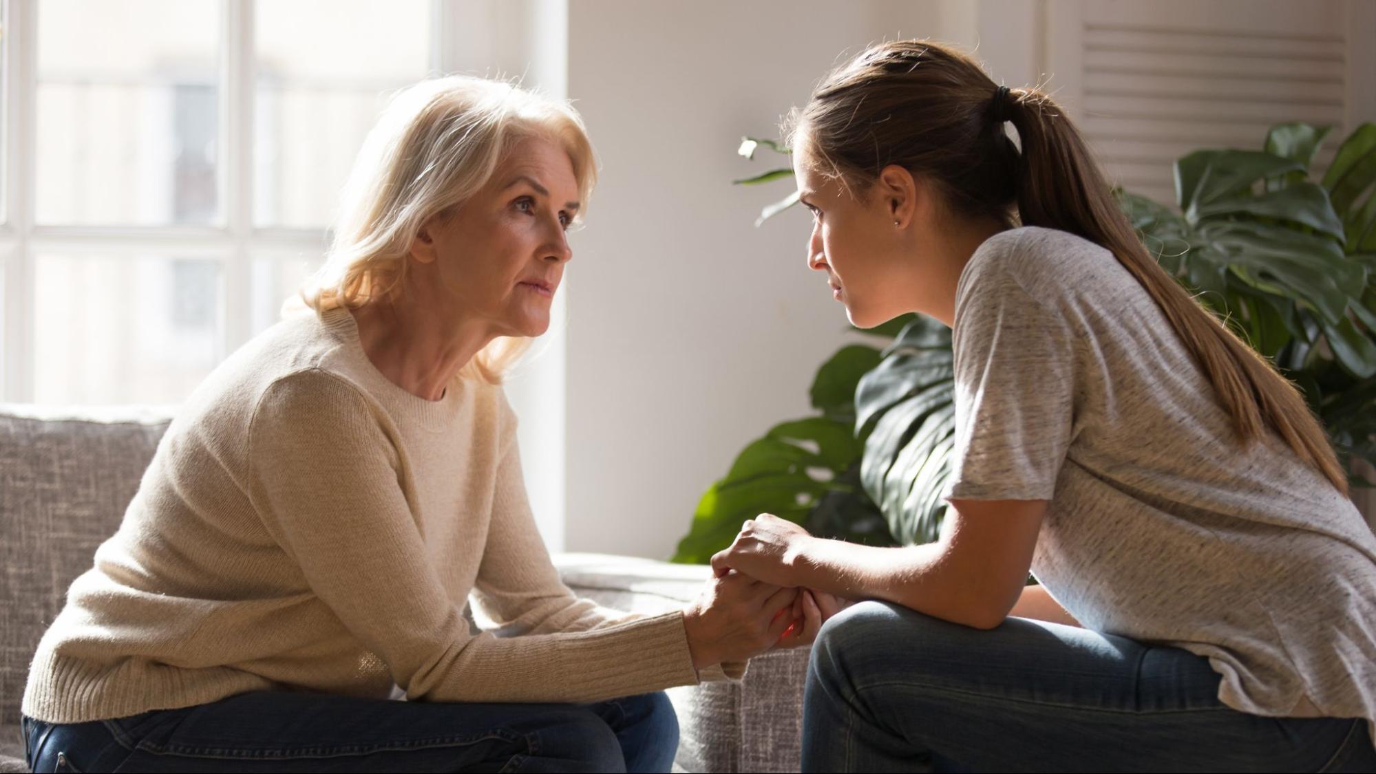 an older parent holding hands with their child as they support their parent with dementia.