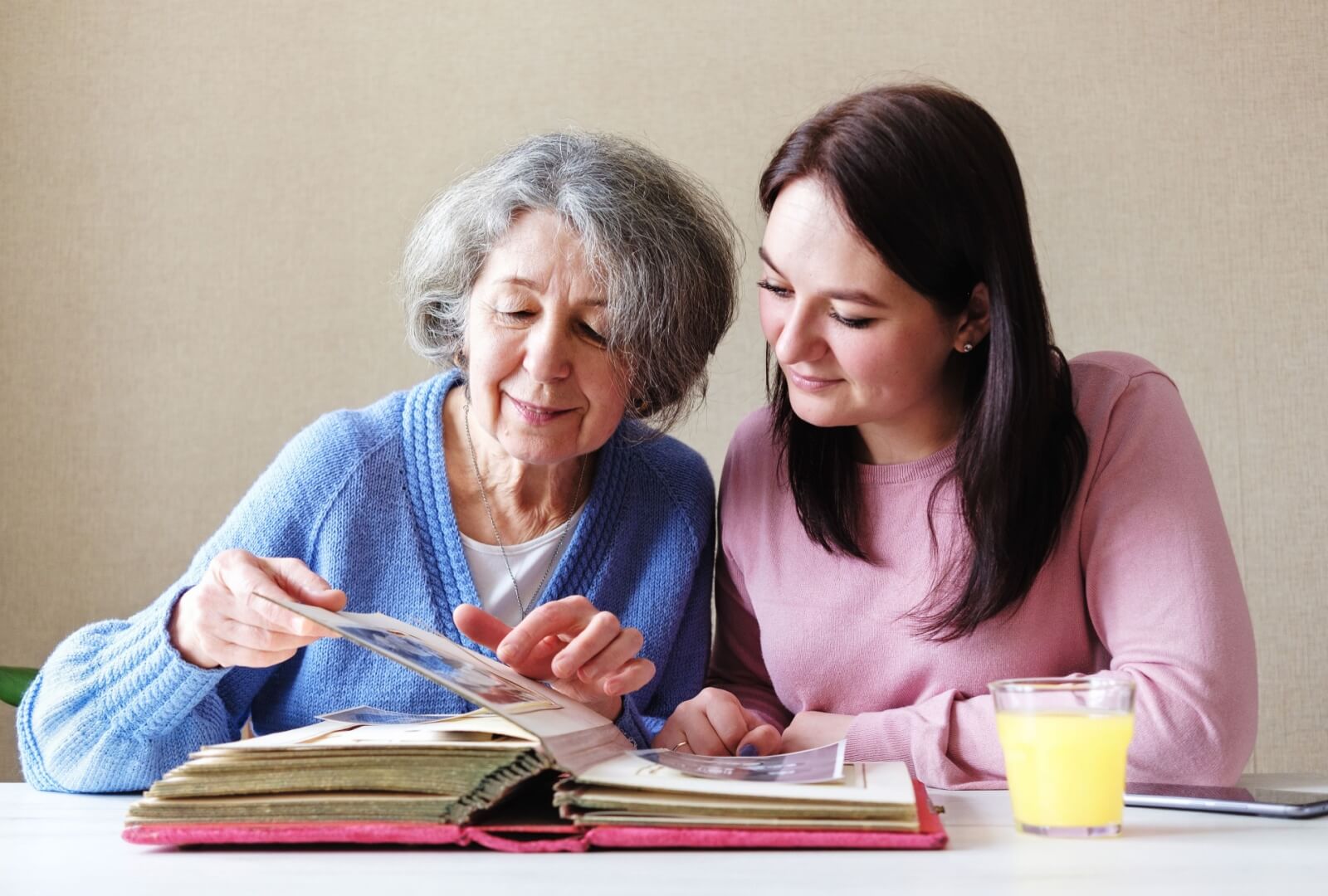 A young woman visiting her mom in an assisted living community & reminiscing over old photos together.