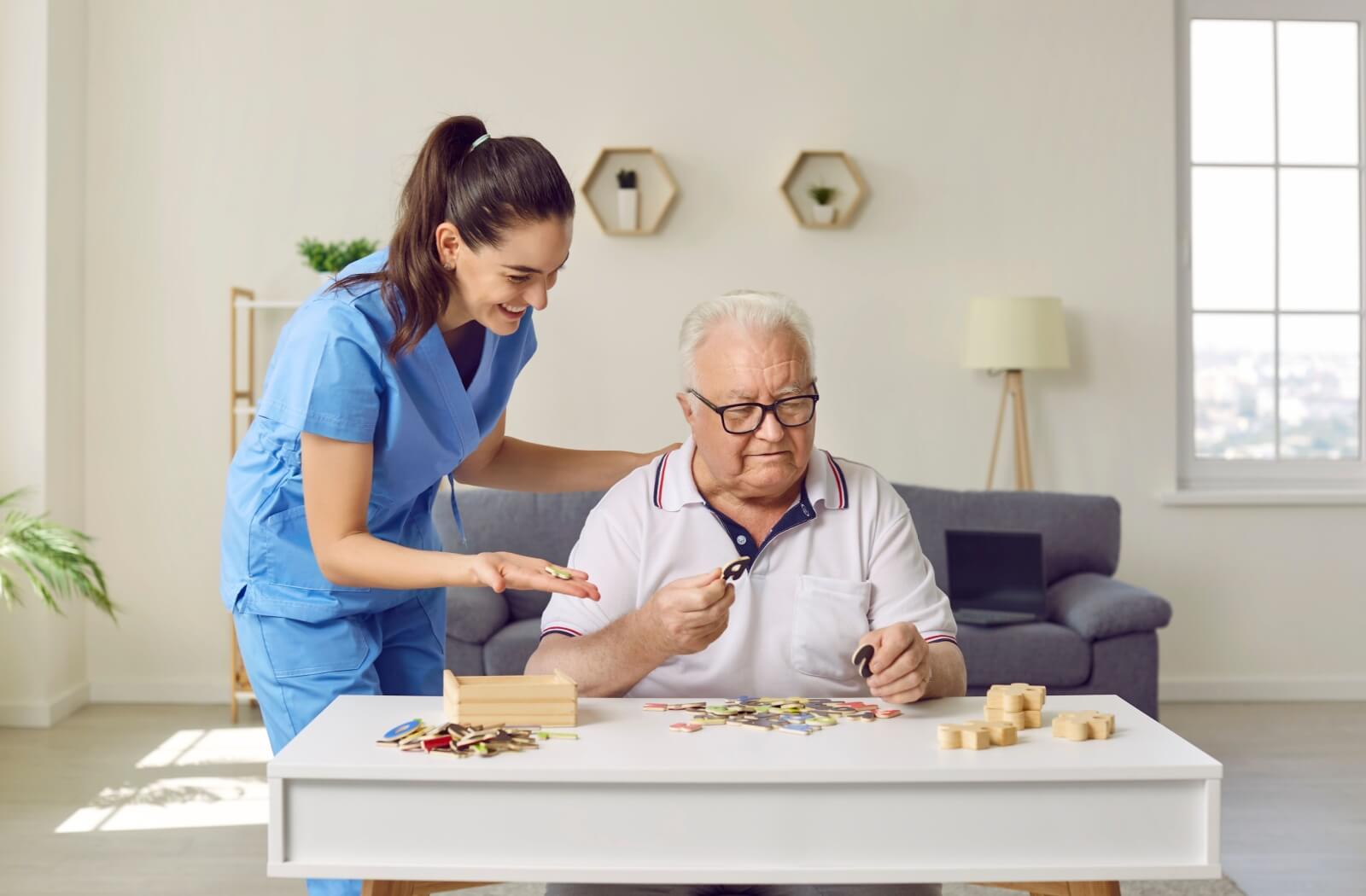 A memory care staff helping a resident to solve a jigsaw puzzle.