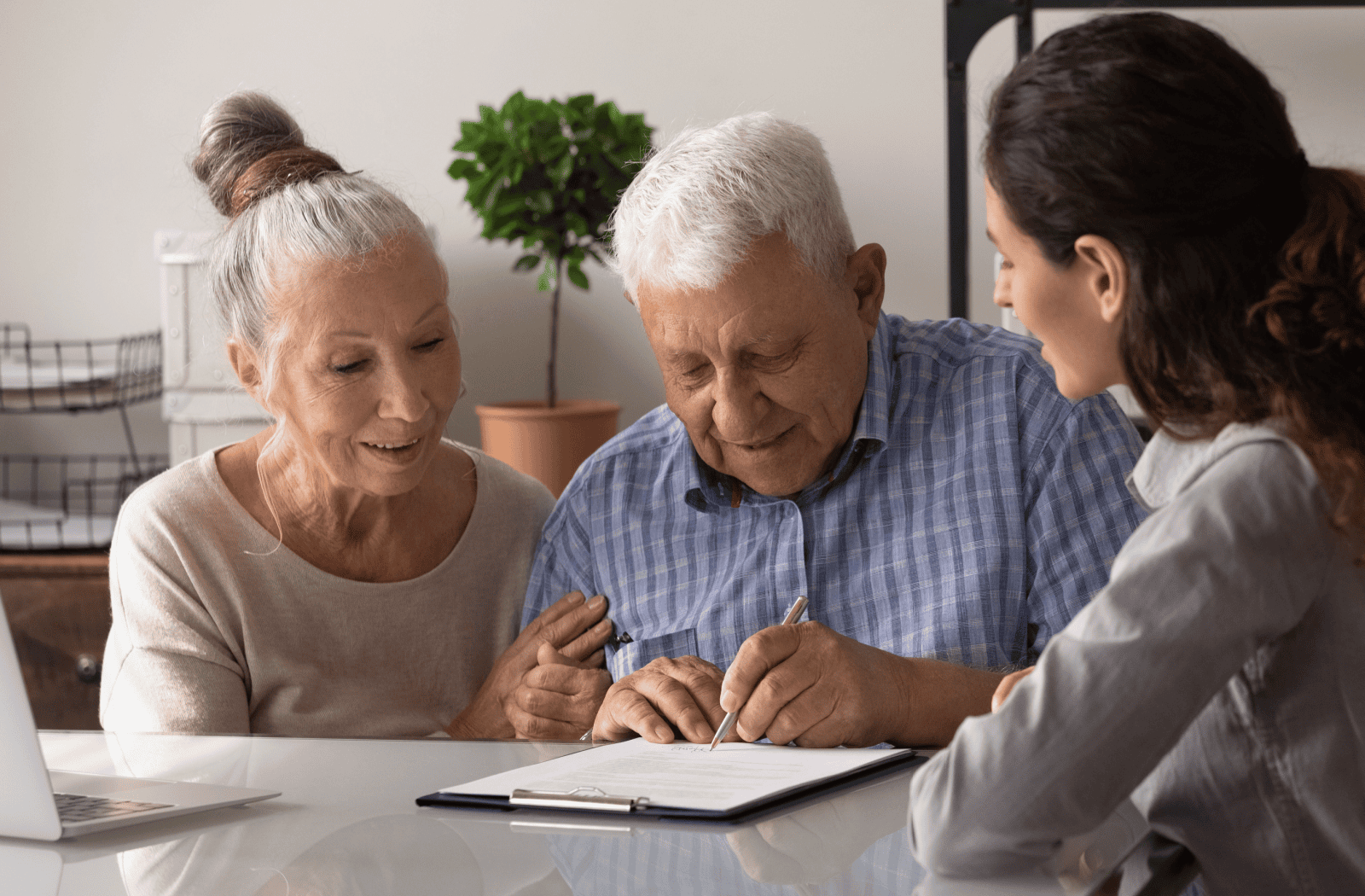 Senior couple sits with a young lawyer to sign Power of Attorney documents.