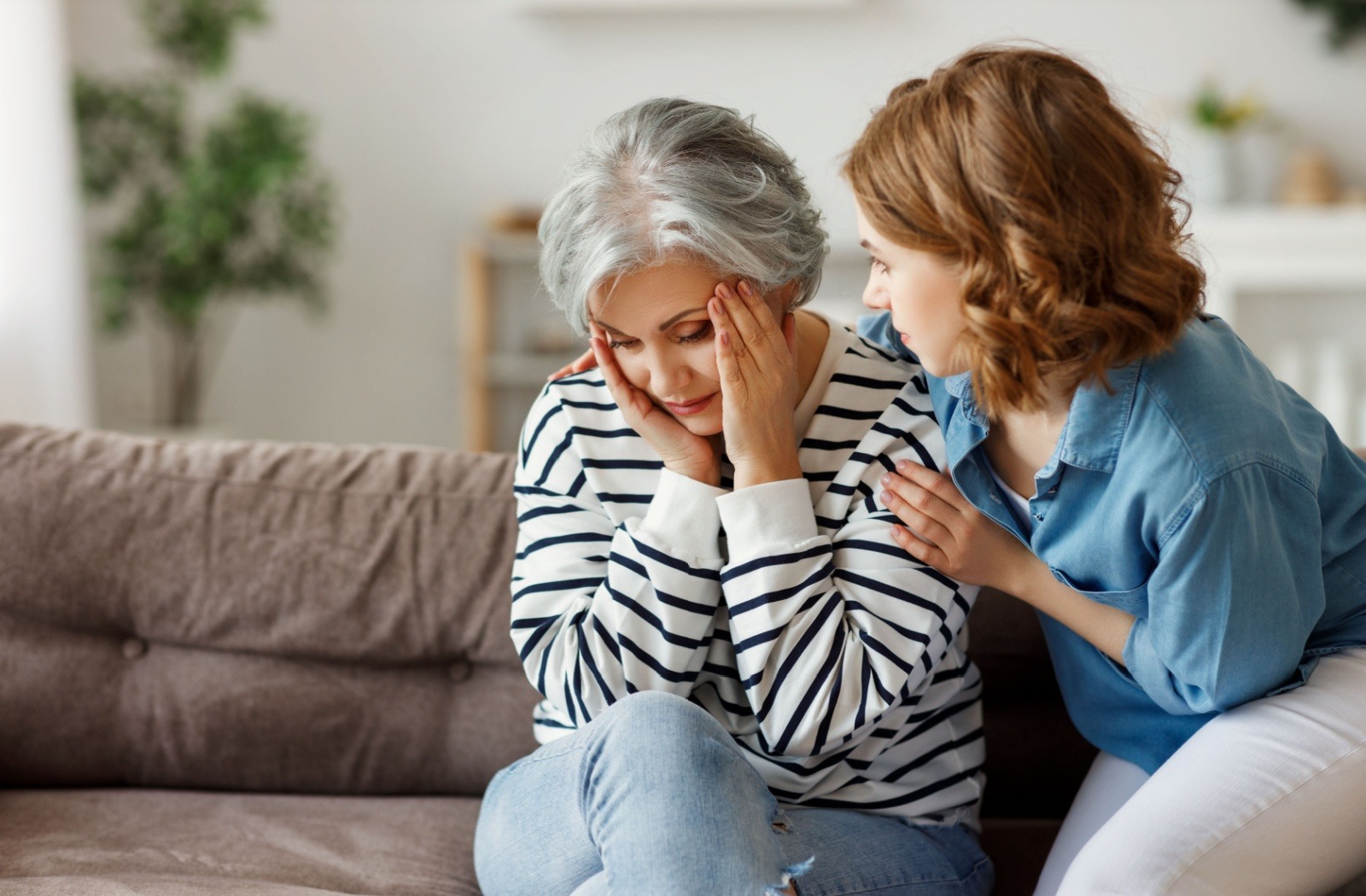 a child supports her senior parent with dementia while sitting on a couch